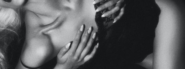 Black and white natural breast escort lying down in black clothing holding breasts