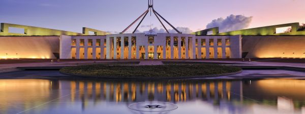 reflection of Canberra Parliament house in fountain pond at sunset